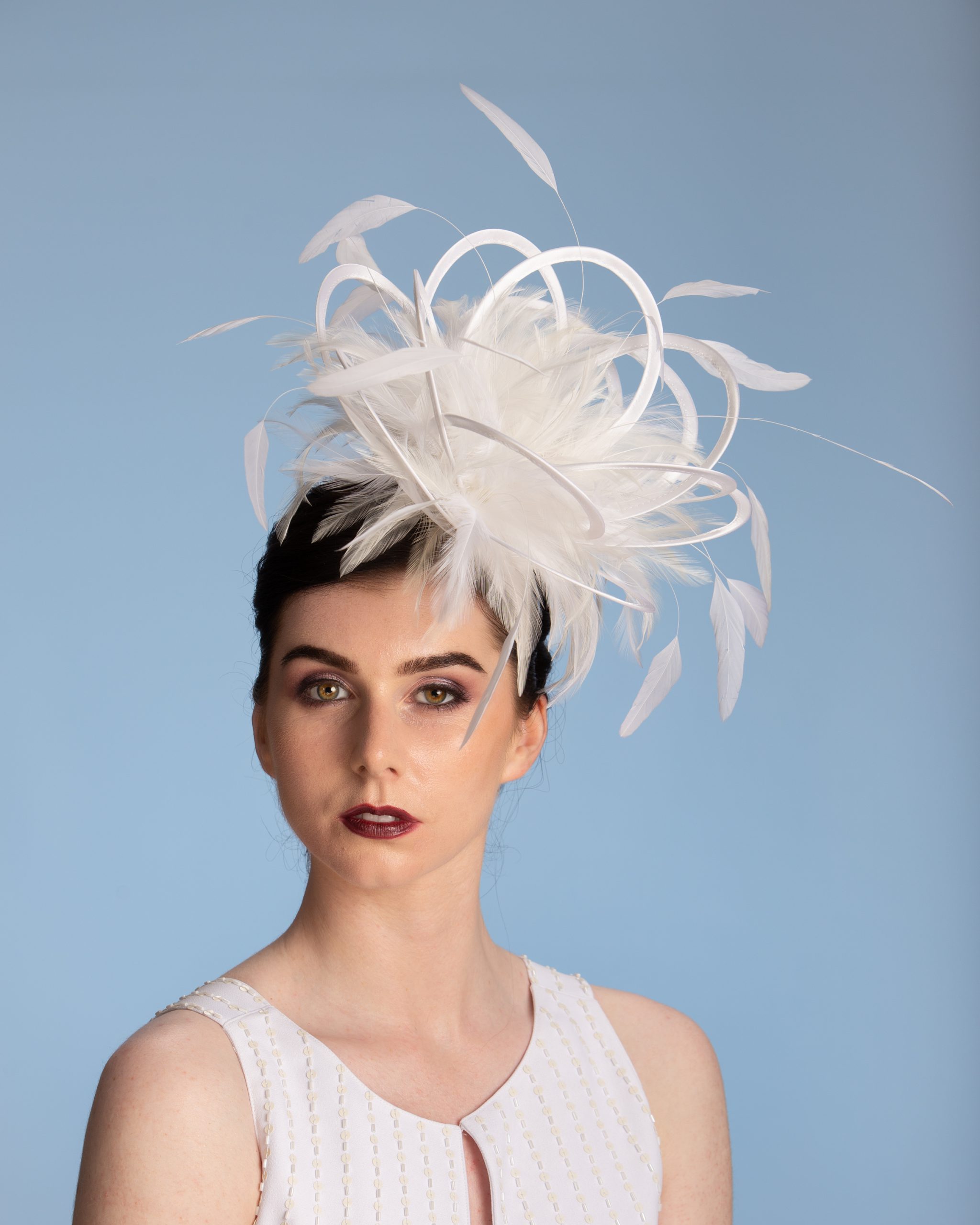 white satin loop and feather fascinator hat set on a headband